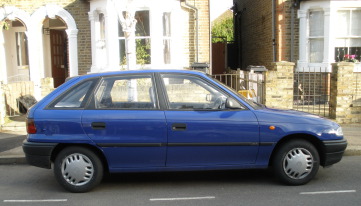 Blue Vauxhall Astra parked in front of semi-detached houses.