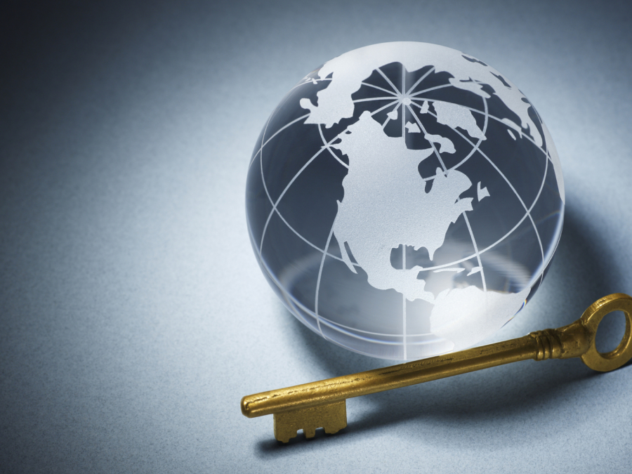 Old-fashioned brass key next to clear Earth marble